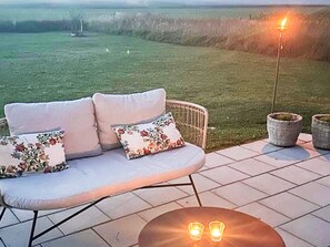 A patio with a cushioned outdoor seating area, a small round table with candles, and a tall lamp post. - 5 Star Holiday Home in Lottorp (Löttorp)