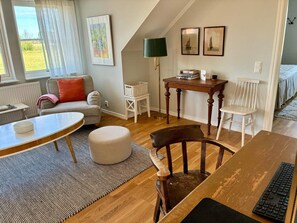 A cozy living room with a wooden dining table, a sofa, a chair, and a lamp. - 5 Star Holiday Home in Lottorp (Löttorp)