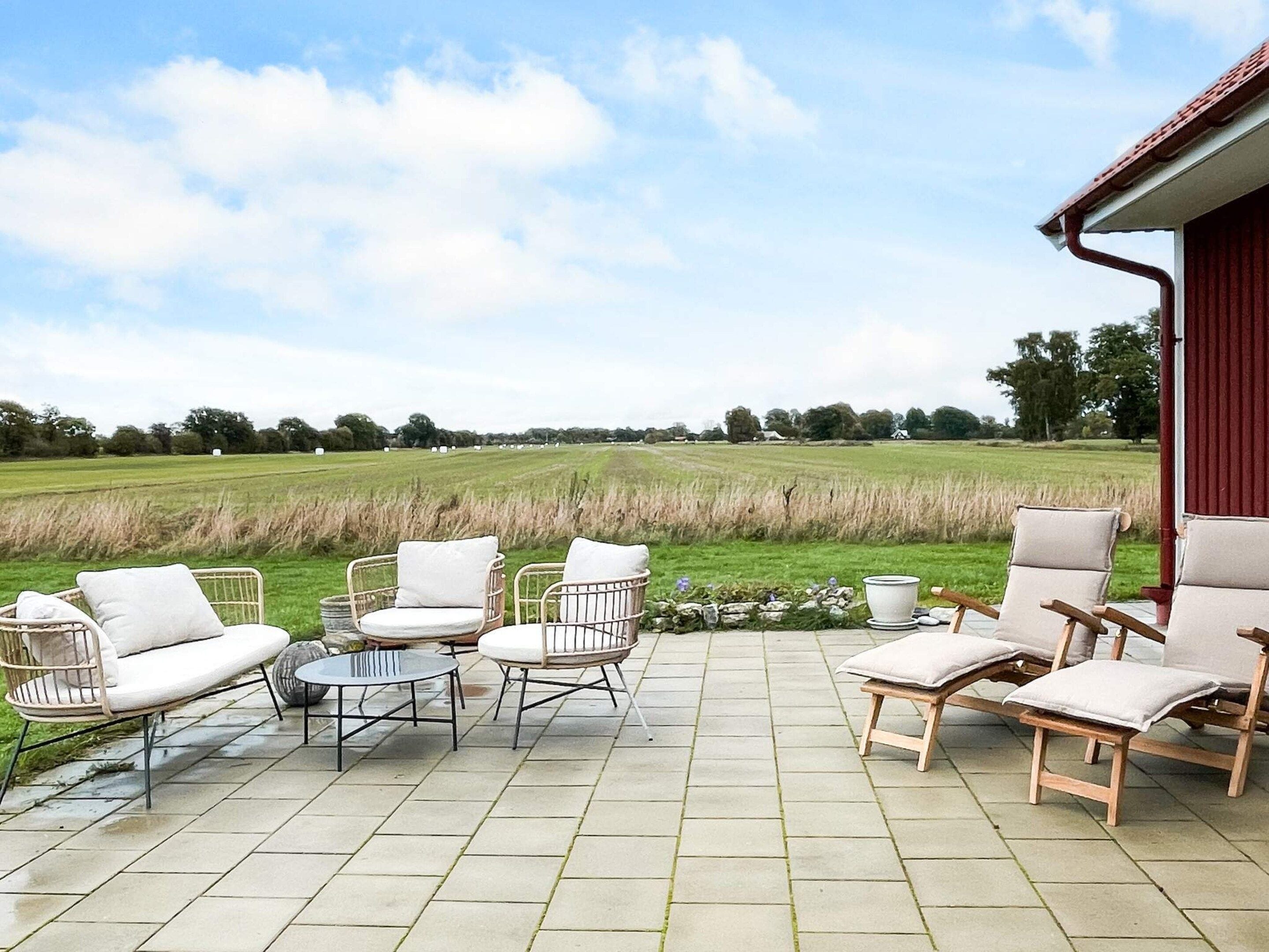 Un patio al aire libre con mobiliario de mimbre y vista a un campo.