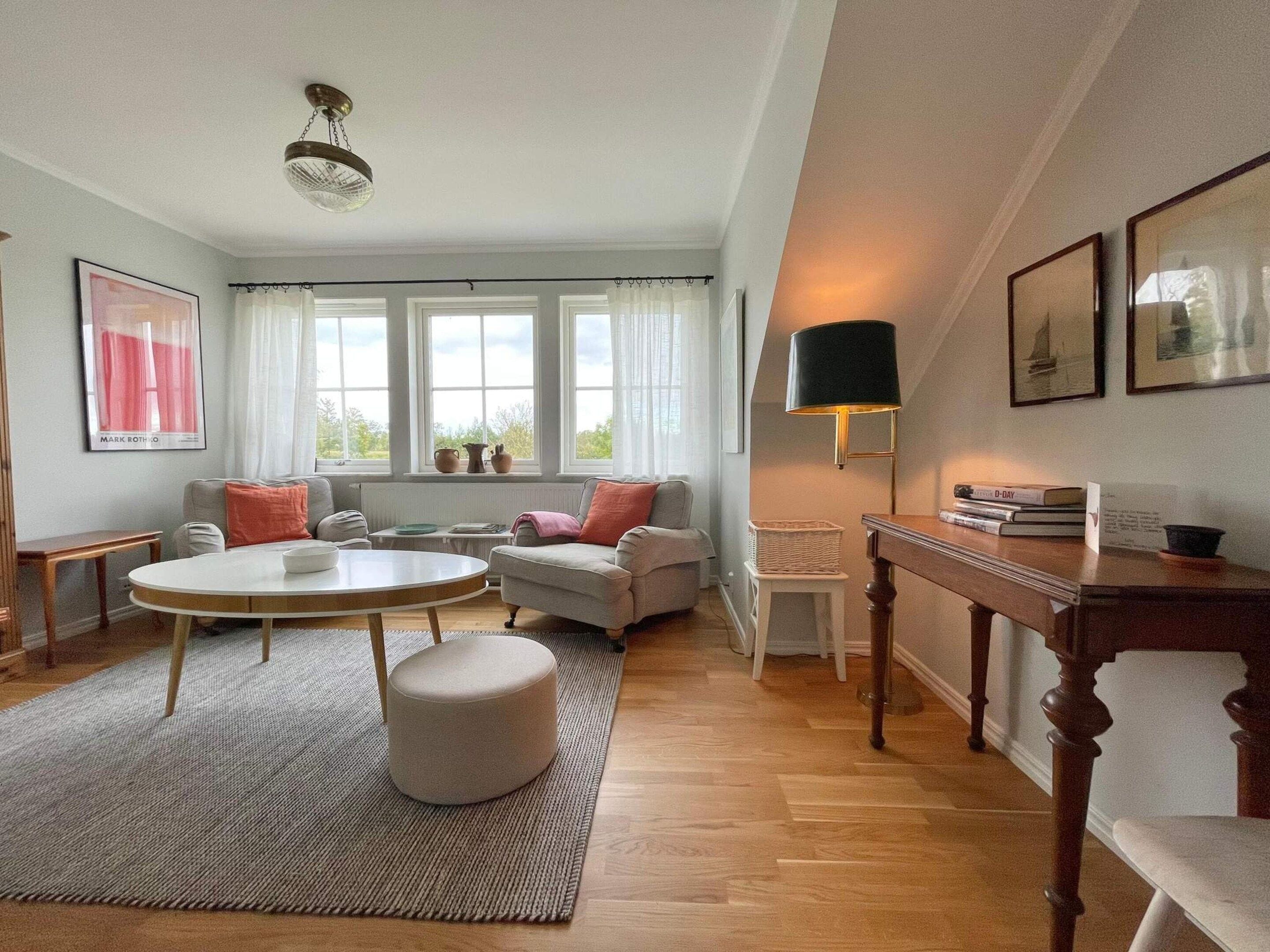 Ein gemütliches Wohnzimmer mit einem runden Couchtisch, einer Couch und einem Beistelltisch mit Büchern.