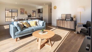 A modern living room with a sofa, coffee table, and a dining area with chairs. - Modern new Homly House at Clyde (Clyde)