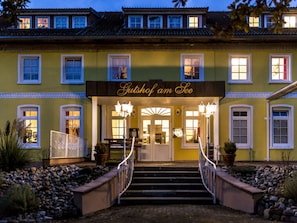 A building with a sign reading "Gutshof am See" and a staircase leading to the entrance. - Courtyard View - Manor by the Lake (Klein Upahl)