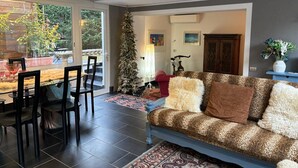 Ein modernes Wohnzimmer mit Sofa, Sesseln, einem Weihnachtsbaum und einem Essbereich mit Tisch und Stühlen.