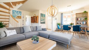 Een moderne woonkamer met een grijze hoekbank, een houten salontafel en een trap.