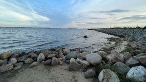 Een rotsachtige kustlijn met kalm water en een heldere lucht.