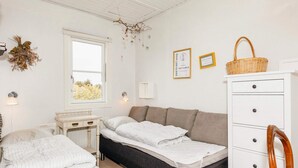 A bedroom with a bed, a desk, a dresser, and a window.