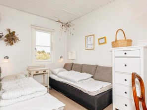 A bedroom with a bed, a desk, a dresser, and a window.