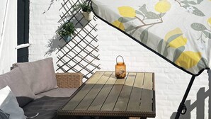A wicker sofa, a small table, and a hanging plant against a white wall.