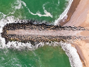 An aerial view of a coastal pier extending into the ocean, with waves crashing against it. - 6 Person Holiday Home in Vestervig (Vestervig)