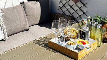 En træbakke med glas, flasker og snacks på en dæk.