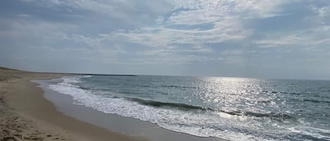 A beach with a clear sky and sunlight reflecting on the water.