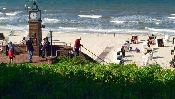 A beach with a clock tower, people walking, and beach chairs. - Lagoon on the Wadden See on Wangerooge (Wangerooge)