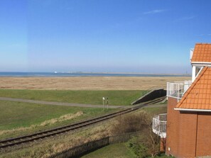A coastal view with a building featuring a red roof and a balcony.