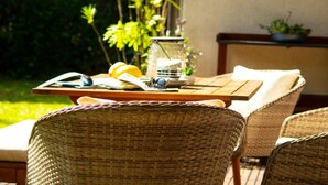 A wicker chair, a wooden table with a glass jar, and a potted plant in a garden setting. - Holiday Apartment Am Buchbuhl (Stockach)