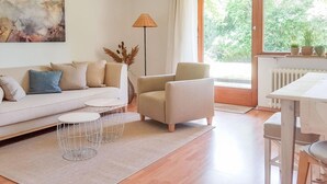 A modern living room with a sofa, armchair, coffee table, and a dining table. - Holiday Apartment Am Buchbuhl (Stockach)