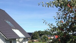 A single-story house with a sloped roof, a small patio with a table and chairs, and a well-maintained lawn. - Holiday Apartment Sandpiper Ground Floor (Klütz)