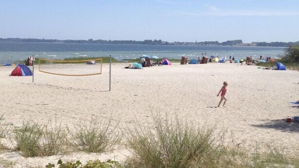A beach with a volleyball net, tents, and people. - Holiday Apartment Sandpiper Ground Floor (Klütz)