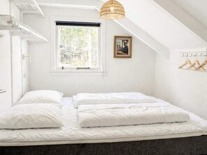Une chambre à coucher avec un lit, une fenêtre, un luminaire suspendu et un porte-manteau.