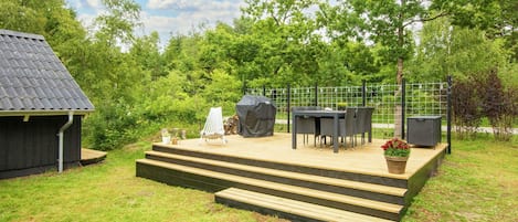 Une terrasse dotée de mobilier d’extérieur et d’un barbecue, entourée d’un jardin clos.