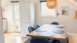 Ein Essbereich mit Holztisch, sechs Stühlen und einer Pendelleuchte.
