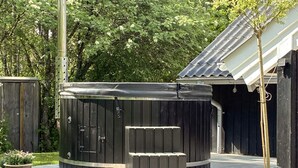 Ein Whirlpool mit Holzterrasse, umgeben von viel Grün.