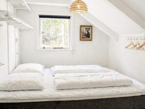 Un dormitorio con cama, ventana, lámpara colgante y perchero.