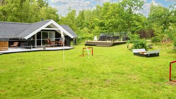 A house with a covered patio, a fenced outdoor area with a table and chairs, and a grassy yard.
