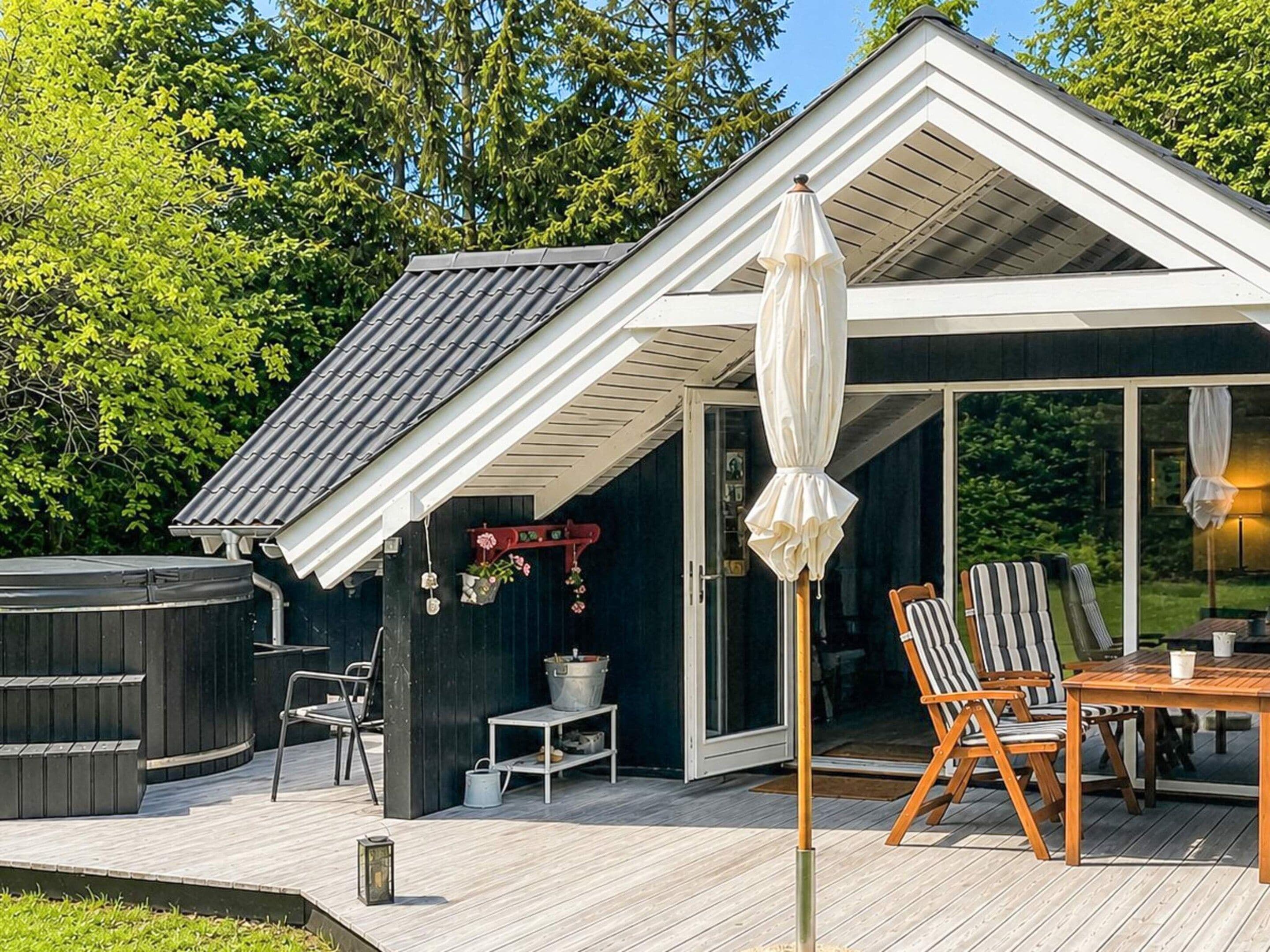 A modern outdoor deck with a hot tub, a table with chairs, and a covered seating area.