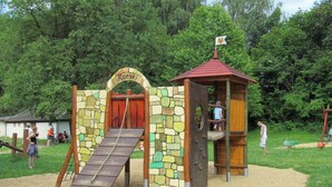 Zona de jocs infantil amb una estructura per escalar, tobogan i un petit edifici de fusta anomenat "Rorse".