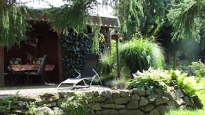 Un pati amb una paret de pedra, una taula amb cadires i una cadira relaxant.