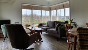 A spacious living room with a large window, a sofa, a coffee table, and a TV. - Canal-side Stay, Giethoorn (Giethoorn)