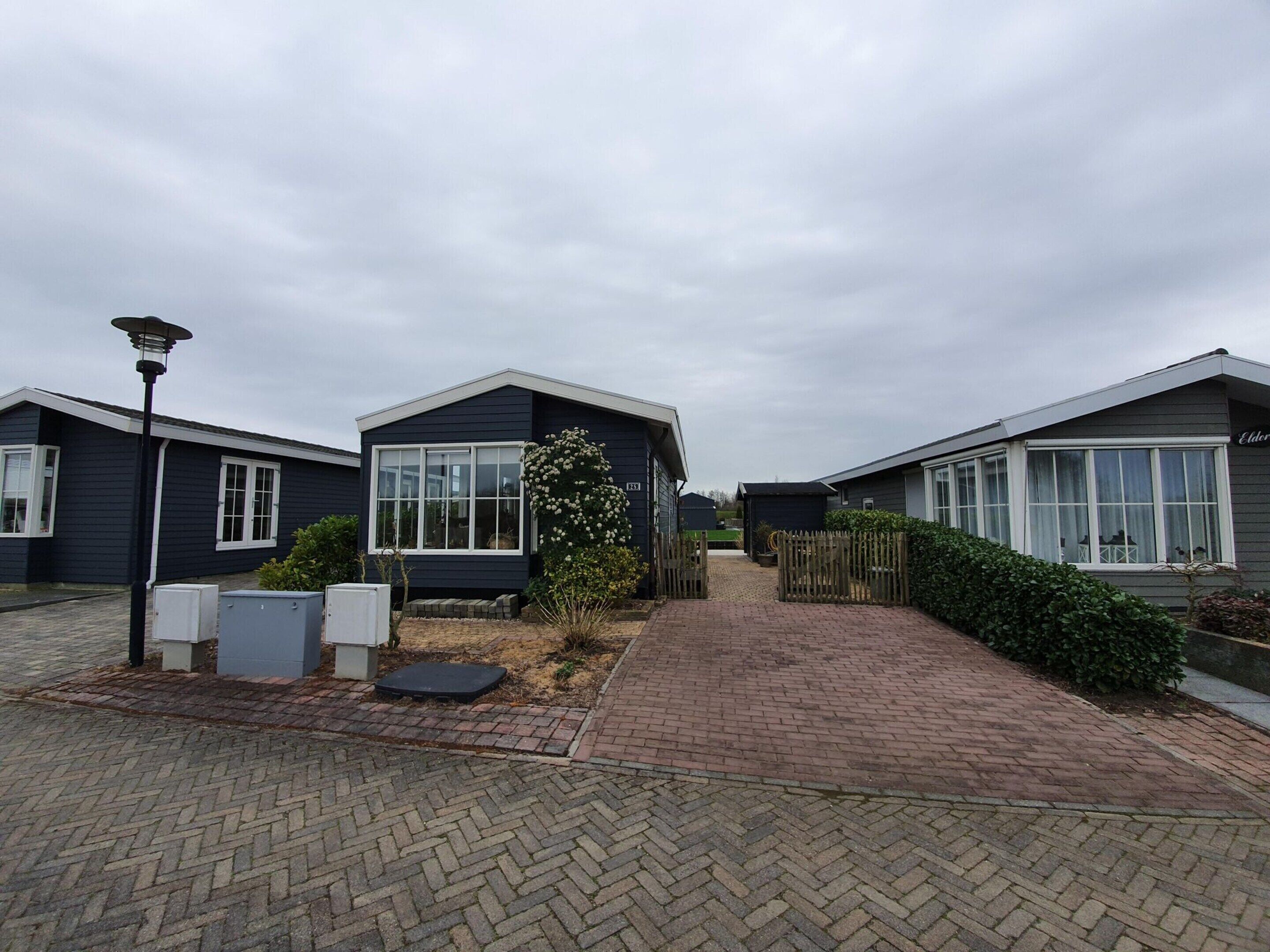 A row of modern, dark-colored mobile homes with large windows and a paved walkway.
