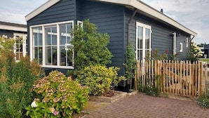 A modern two-story house with a dark exterior, large windows, and a brick pathway leading to the entrance. - Canal-side Stay, Giethoorn (Giethoorn)