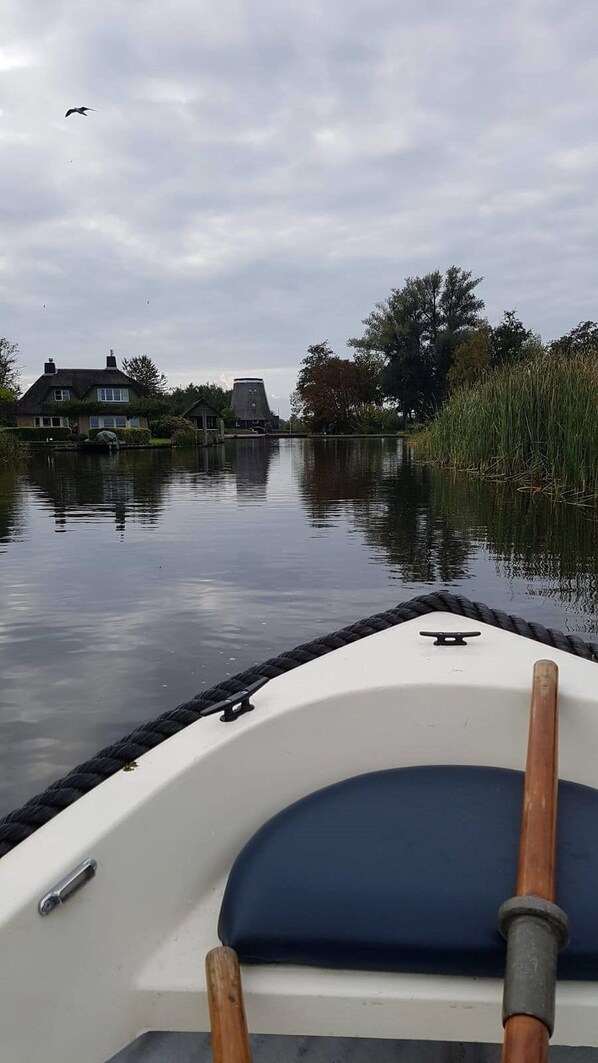 Un bote en un río tranquilo con casas y árboles al fondo.