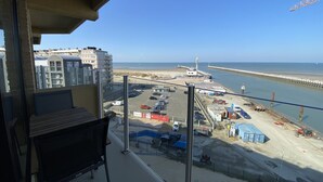 A view from a balcony overlooking a beach, a parking lot, and a pier. - Apartment in Nieuwpoort With Sea Views (Nieuwpoort)