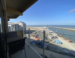 Une vue depuis un balcon donnant sur une plage, un parking et une jetée.