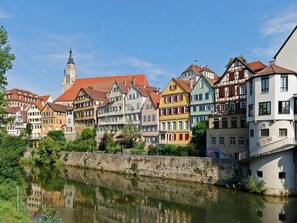 Une rangée de bâtiments européens traditionnels aux couleurs vives, le long d’une rivière.