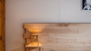 A bedroom with a wooden headboard, a bedside lamp, and a bed with white bedding. - Apartment on Belgian Coast With Sea View (Koksijde)