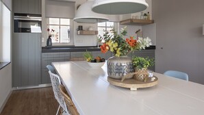 A modern kitchen with grey cabinets, a white island, and a large hanging light fixture.