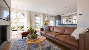 A modern living room with a brown leather sofa, a wooden coffee table with decorative items, and a patterned rug.