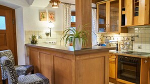 A kitchen with wooden cabinets, a central island with a plant, and a dining area with patterned chairs. - Posthof Holiday Guesthouse (Waldmuenchen)