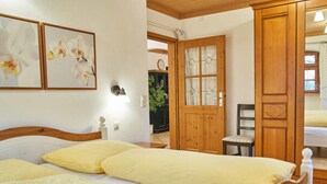 A bedroom with two beds, wooden furniture, and a door leading to another room. - Posthof Holiday Guesthouse (Waldmuenchen)