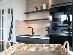 A modern kitchen with a black Bosch oven, a built-in sink, and a wicker basket on the counter. - Reethuus Nord Modern Retreat (Juist)