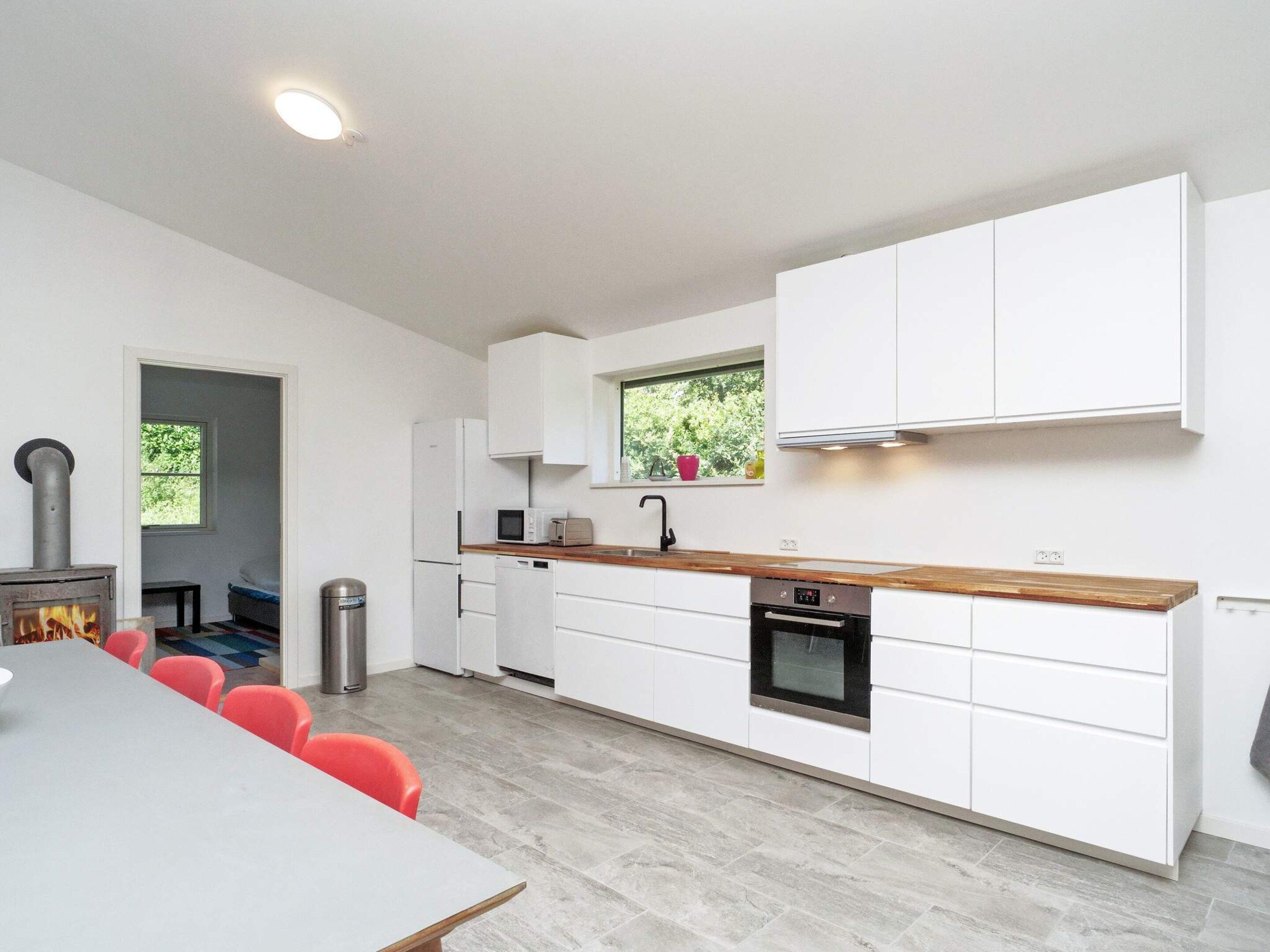 Una cocina moderna con armarios blancos, encimera de madera y horno empotrado.