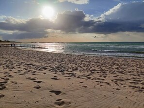 A beach with footprints, a wooden walkway, and the ocean. - 4 Star Holiday Home in Melby (Melby)