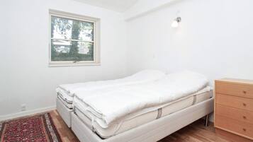 Een slaapkamer met een bed, een kaptafel, een raam en een vloerkleed.