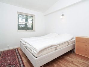 A bedroom with a bed, a dresser, a window, and a rug. - 4 Star Holiday Home in Melby (Melby)