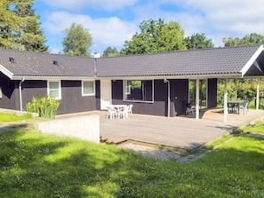 Un bâtiment à deux étages doté d’un patio couvert, d’un petit jardin et d’une terrasse en bois.