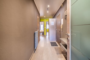 A hallway with a radiator, a door, and a light fixture. - Apartment Near Dunes With Sea View (Koksijde)