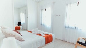A modern hotel room with a large bed, a chair, and a mirror.